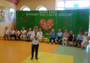 Chłopiec trzyma w ręku mikrofon, recytuje wiersz.